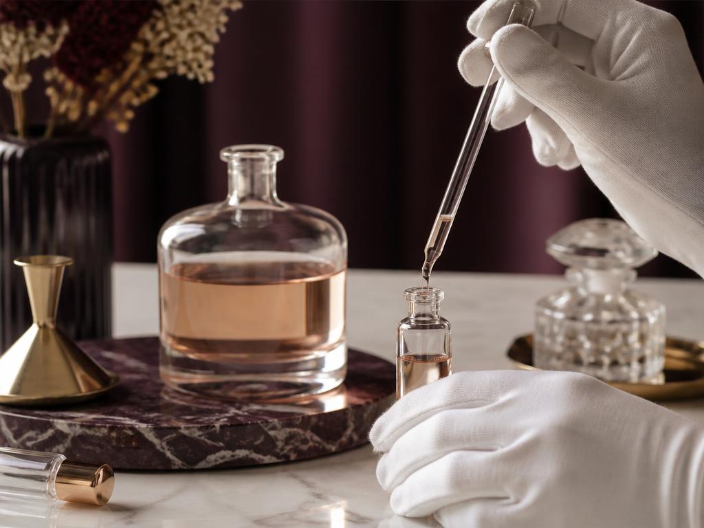 Ręce w rękawiczkach napełniające małą fiolkę z odlewką pipetą na marmurowym blacie